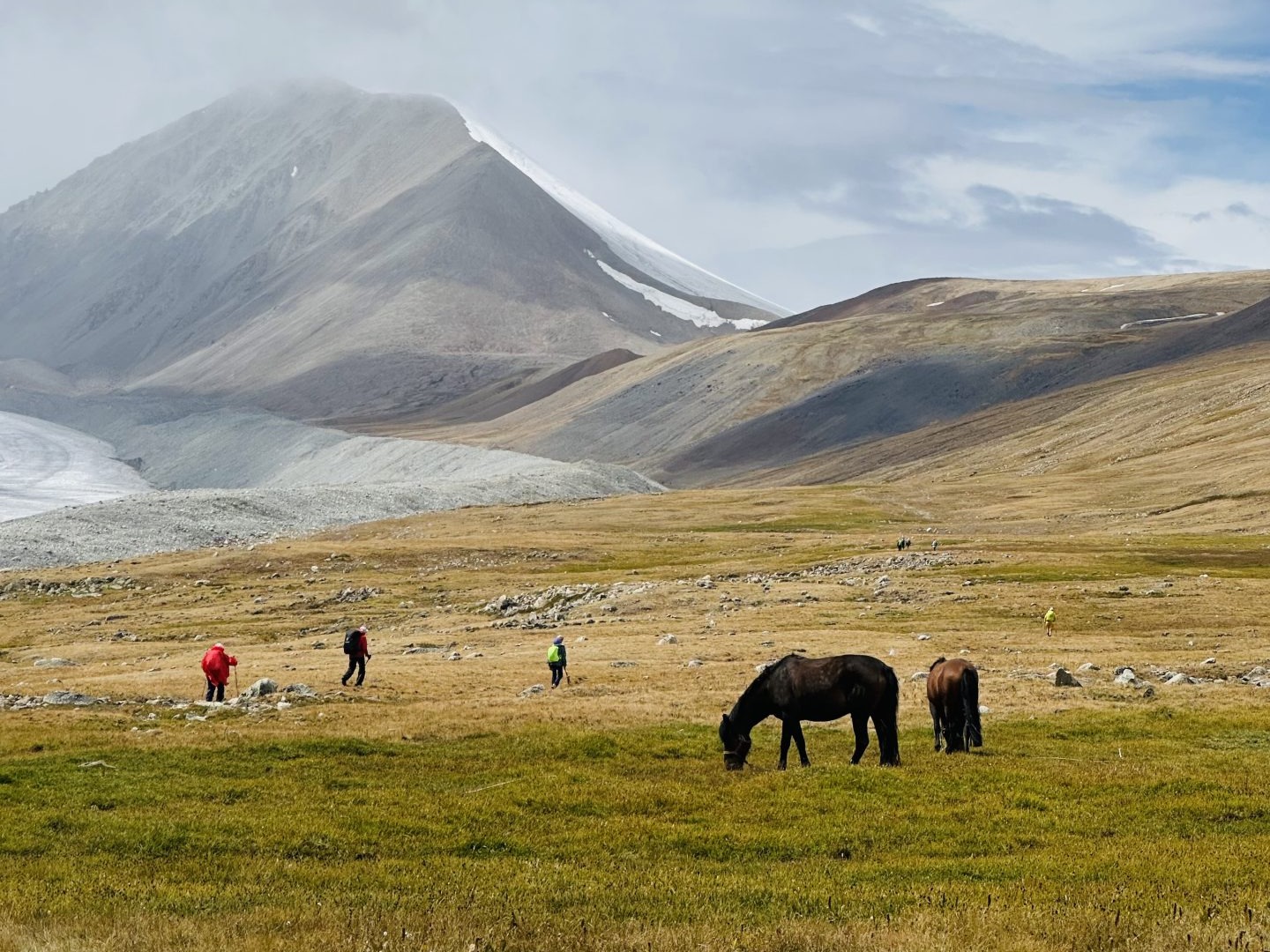 Trekkers and pack horses resting above a glacial moraine in the Altai