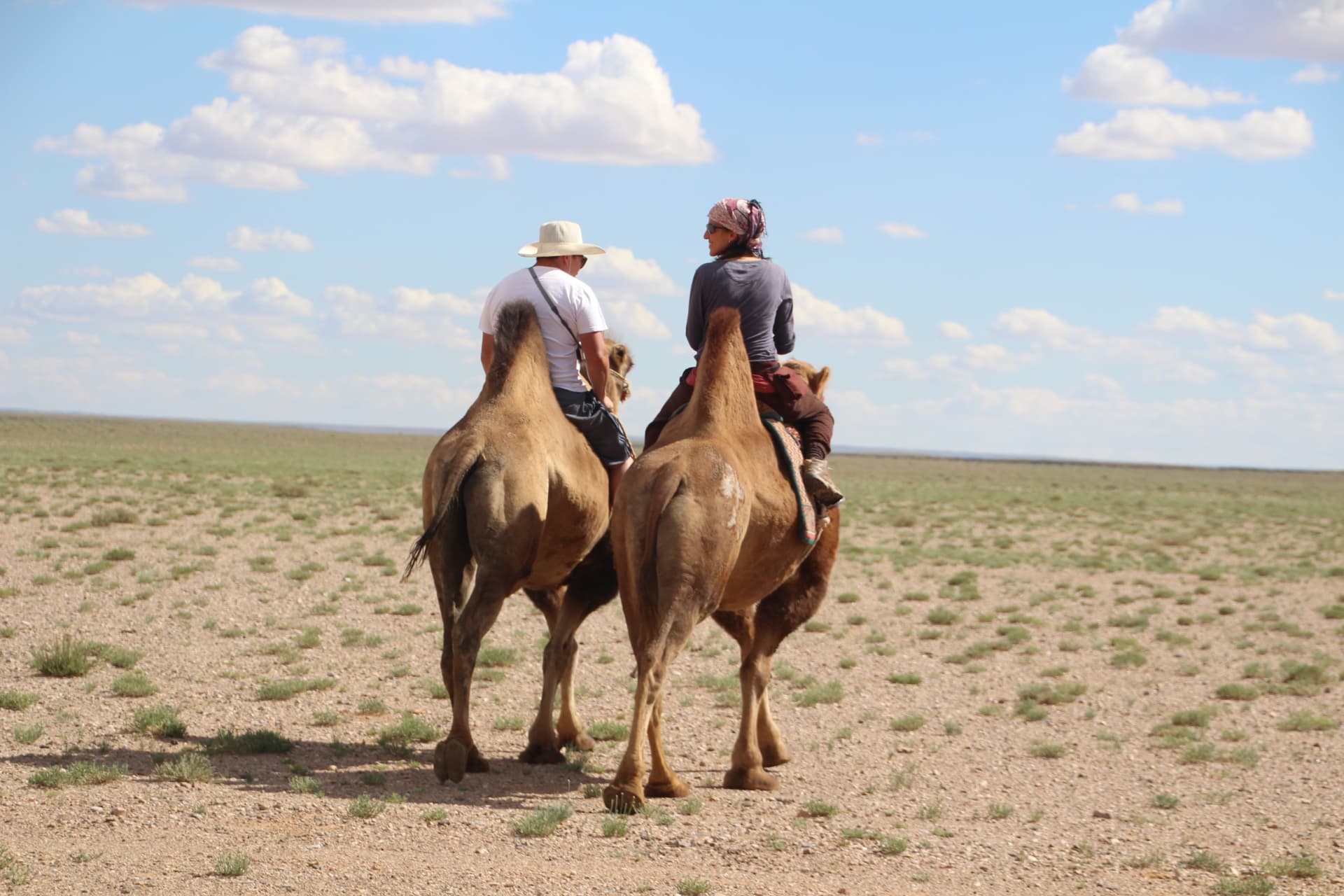 Two travellers riding Bactrian camels across the open Gobi