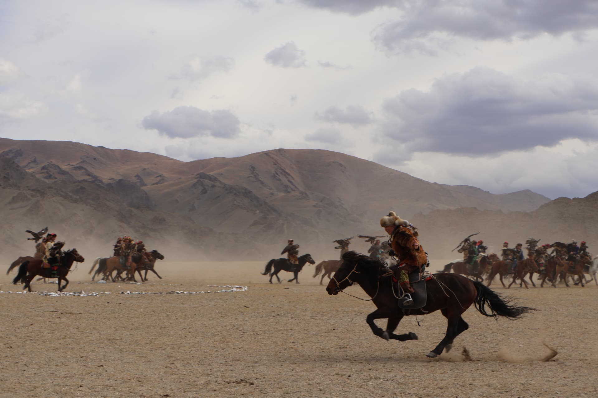 Eagle hunters galloping across the plain during the Golden Eagle Festival