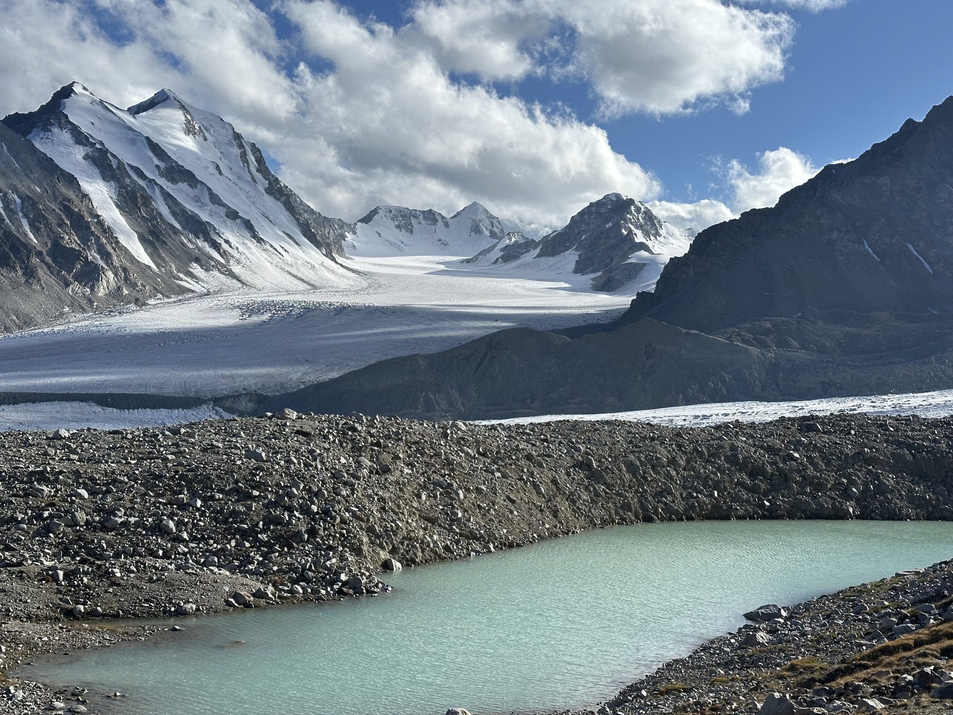 Turquoise glacial lake beneath the snow peaks of Altai Tavan Bogd