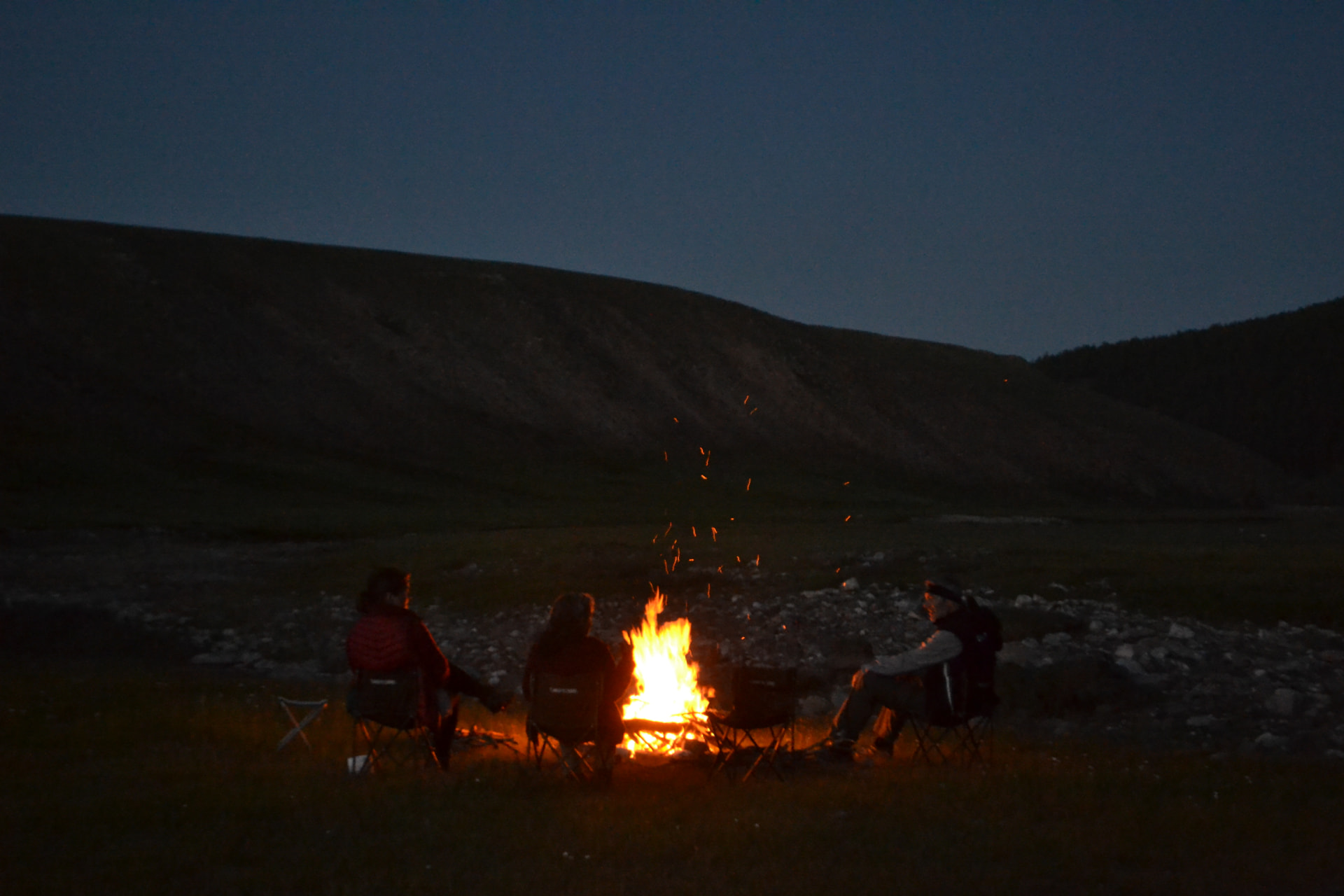 Travellers sitting around a campfire under the night sky